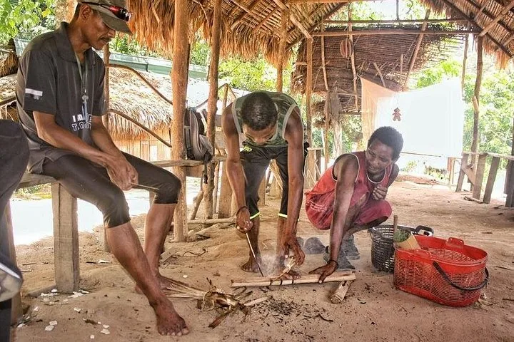 Indigene Menschen, die in einer traditionellen Hütte zeigen, wie man Feuer macht.